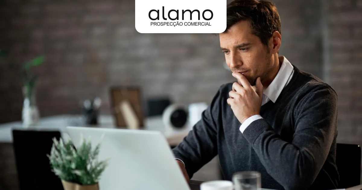 Profissional pensativo analisando informações no notebook em ambiente de escritório, com logo da Álamo Prospecção Comercial no topo.